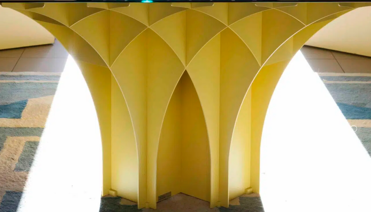 Yellow architectural structure with geometric design on a tiled floor