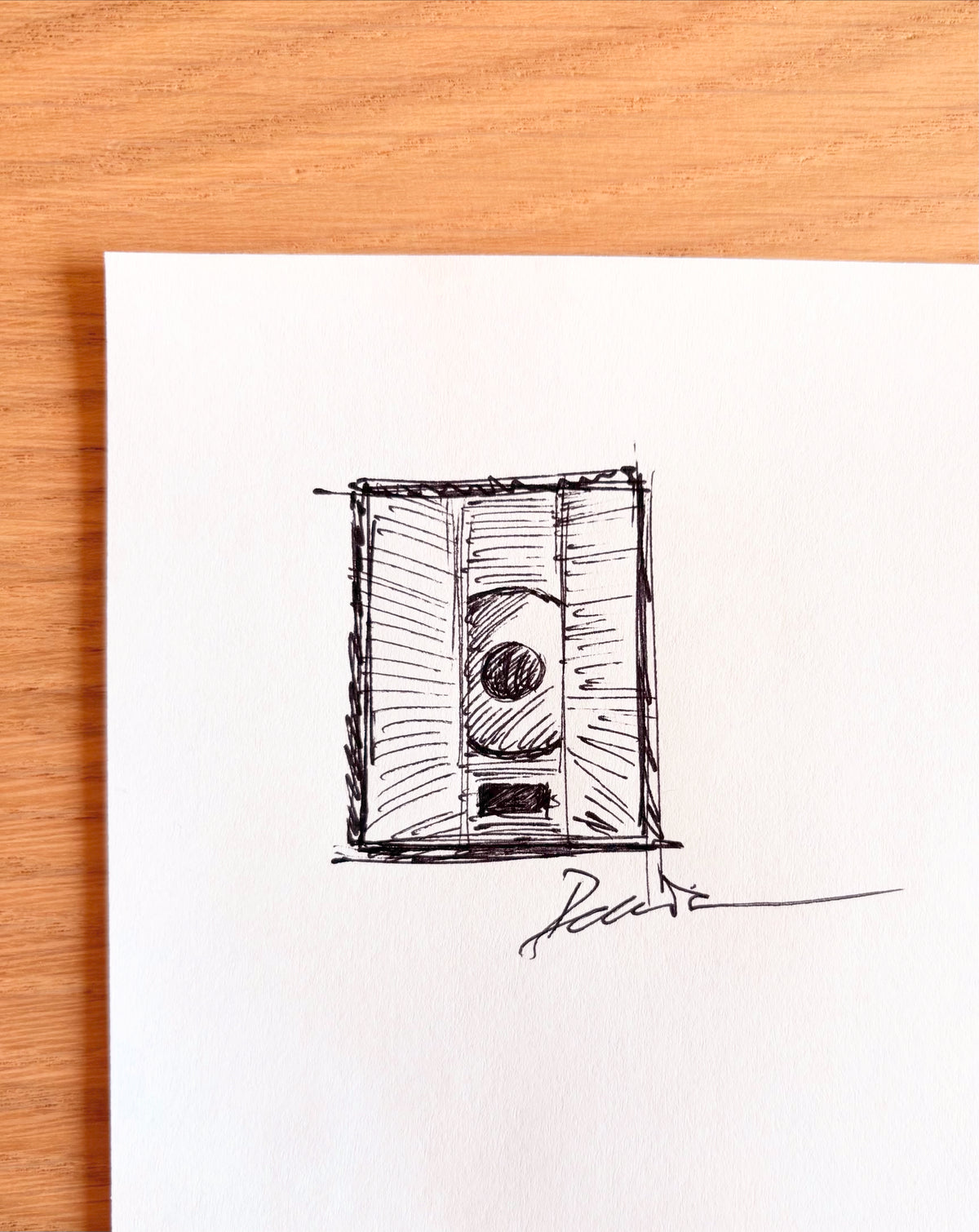 Small black and white drawing of a cassette tape on a white background with a wooden frame.